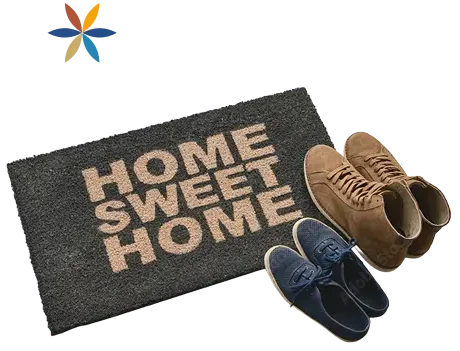 A 'Home sweet home' doormat with two pairs of shoes beside it