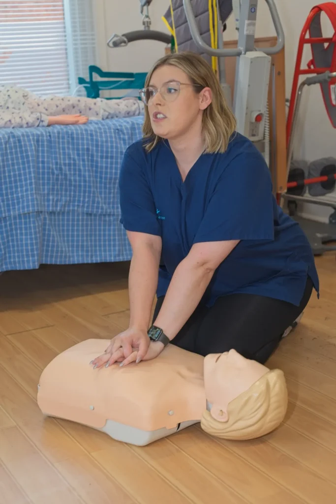 A carer practising CPR on a training manikin