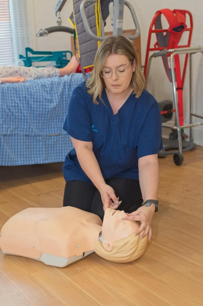 A carer practising chest compressions on a training manikin during first aid training