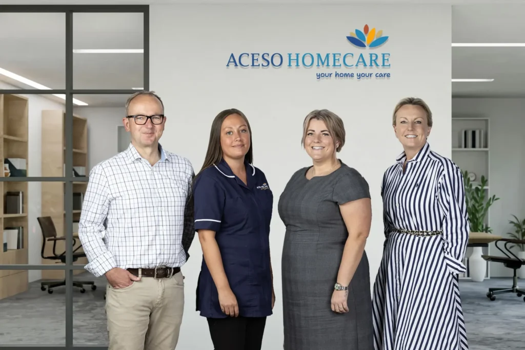 Four members of the Aceso Homecare team in their office beneath the Aceso Homecare sign